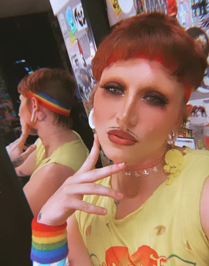 Drag queen porn entertainer Ken Dahl wearing a drawn on mustache and rainbow sweatband accessories.